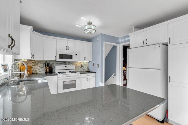 kitchen with sink, white cabinetry, tasteful backsplash, dark stone countertops, and white appliances