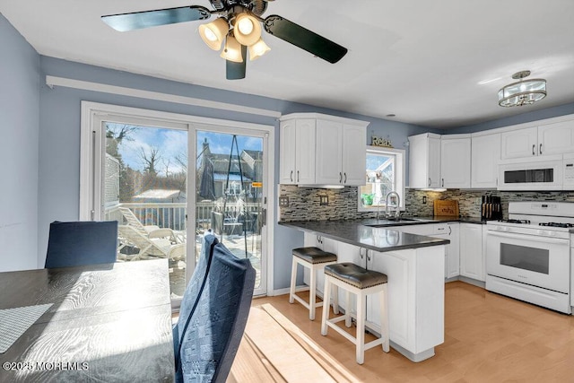 kitchen featuring sink, white appliances, kitchen peninsula, and white cabinets