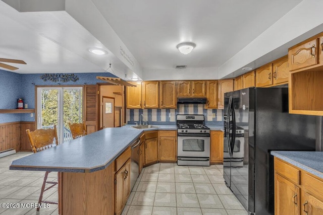 kitchen featuring appliances with stainless steel finishes, sink, a breakfast bar area, ceiling fan, and kitchen peninsula