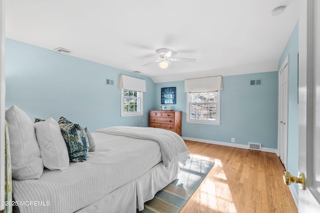 bedroom with ceiling fan, multiple windows, and light hardwood / wood-style flooring