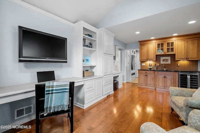 interior space with sink, wine cooler, built in desk, light hardwood / wood-style floors, and vaulted ceiling