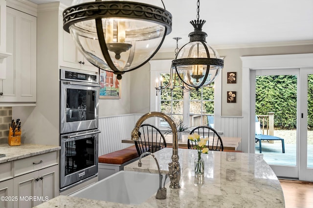 kitchen featuring ornamental molding, light stone countertops, and double oven