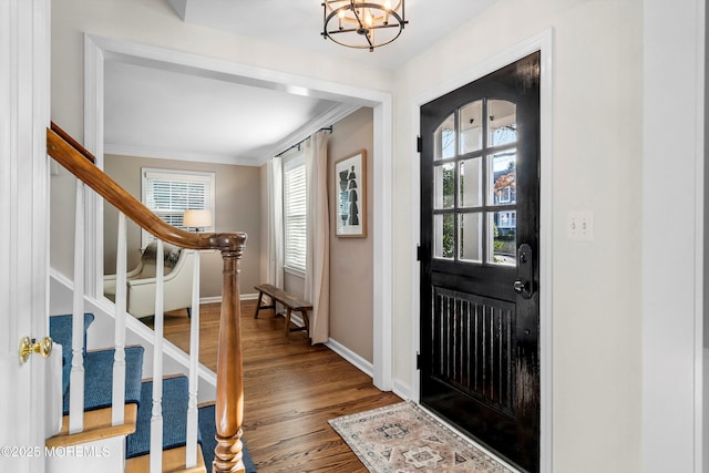 foyer with hardwood / wood-style floors, crown molding, plenty of natural light, and a notable chandelier