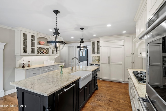 kitchen with sink, white cabinetry, hanging light fixtures, a center island with sink, and paneled built in refrigerator