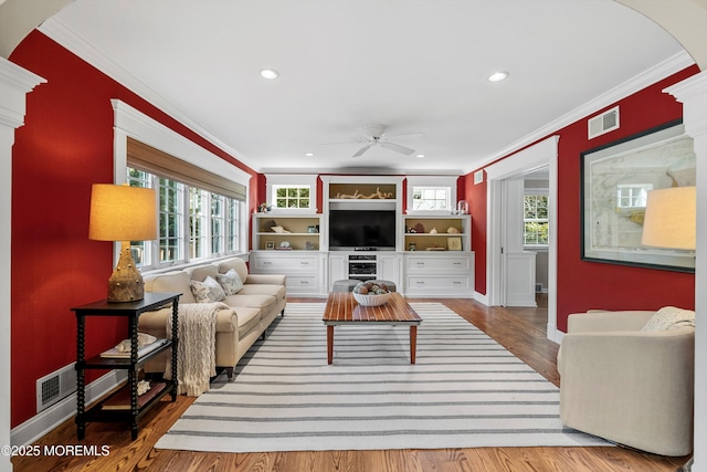 living room featuring ornamental molding, wood-type flooring, and a healthy amount of sunlight