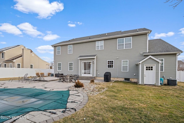 rear view of property with a patio, a covered pool, central AC, and a lawn