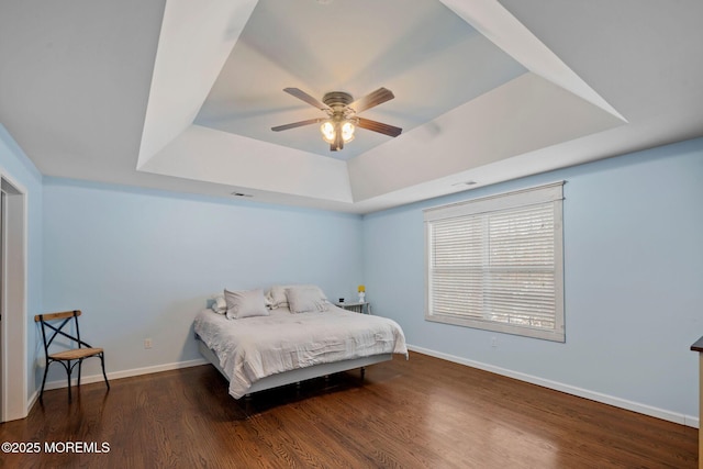 bedroom featuring a raised ceiling, dark hardwood / wood-style floors, and ceiling fan