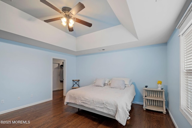 bedroom featuring dark wood-type flooring, ceiling fan, and a tray ceiling