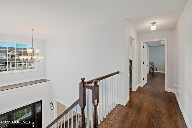 hall featuring dark wood-type flooring and a chandelier