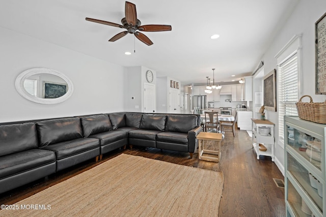 living room featuring dark wood-type flooring and ceiling fan with notable chandelier