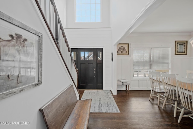 foyer entrance with crown molding, dark hardwood / wood-style floors, a healthy amount of sunlight, and a towering ceiling