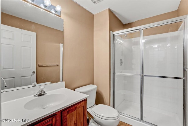 bathroom with a shower with door, vanity, and toilet