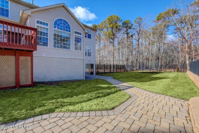 view of yard with a patio, a wooden deck, and a trampoline