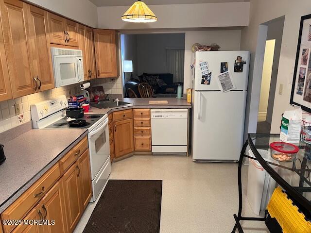 kitchen featuring white appliances, hanging light fixtures, and backsplash