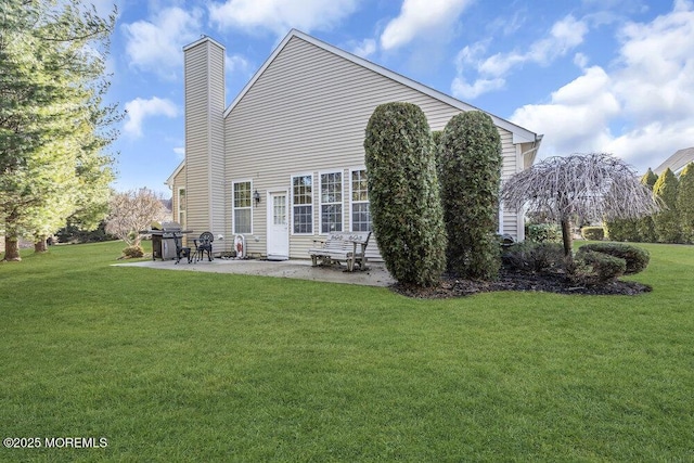 back of house with a lawn, a chimney, and a patio area