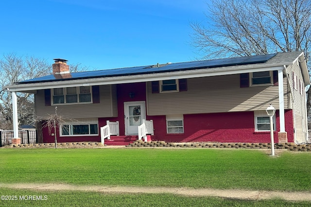 bi-level home with a front lawn and solar panels