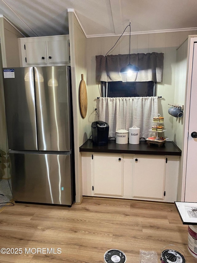 kitchen with white cabinets, stainless steel refrigerator, and light hardwood / wood-style floors