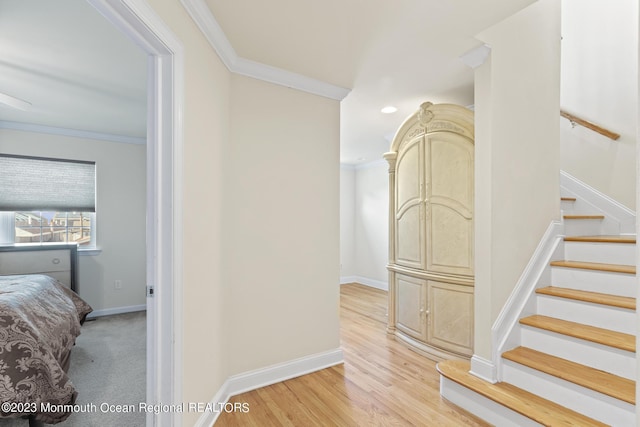 hallway featuring baseboards, stairway, wood finished floors, and crown molding