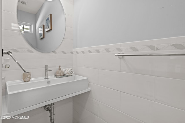 bathroom featuring visible vents and tile walls