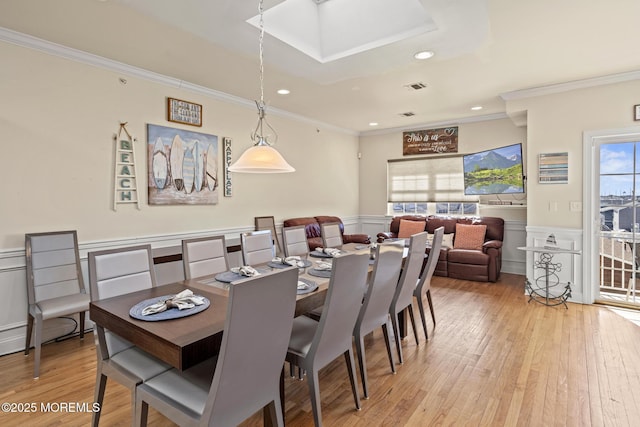 dining room with a wainscoted wall, crown molding, light wood finished floors, recessed lighting, and visible vents