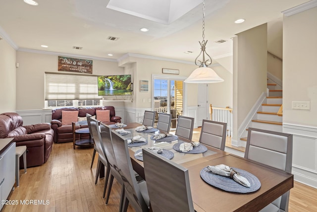 dining area featuring light wood-style floors, visible vents, and stairs