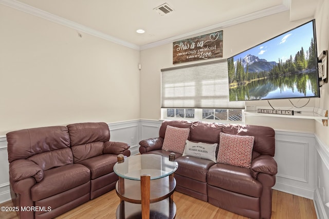 living area featuring light wood-type flooring, ornamental molding, wainscoting, and visible vents