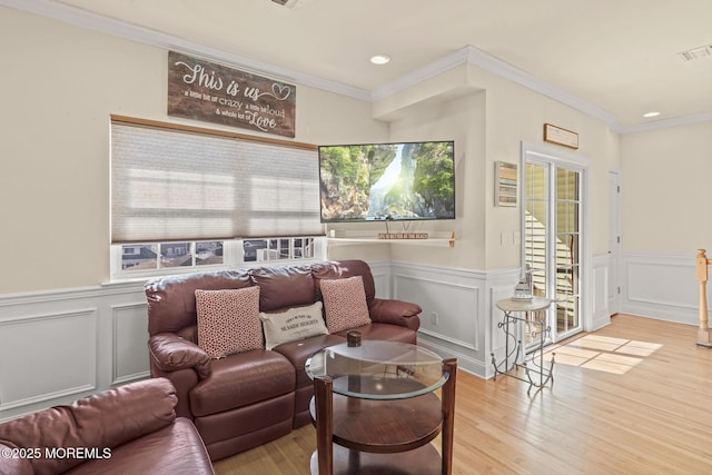 living room featuring a healthy amount of sunlight, light wood-style floors, and ornamental molding