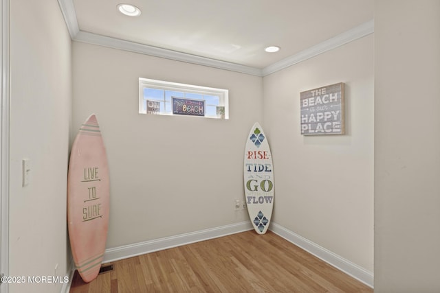 empty room with light wood-style floors, recessed lighting, crown molding, and baseboards