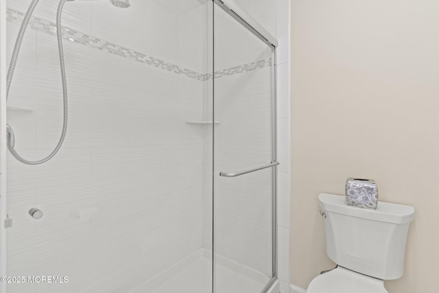 bathroom featuring toilet and a tile shower