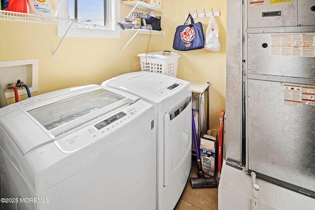 laundry area featuring heating unit, washer and dryer, and light tile patterned floors