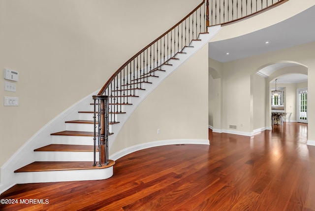 stairs with hardwood / wood-style floors and a high ceiling