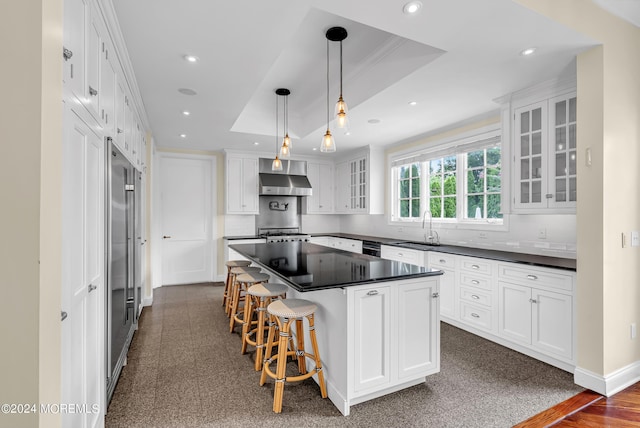 kitchen featuring a kitchen island, sink, white cabinets, hanging light fixtures, and a raised ceiling