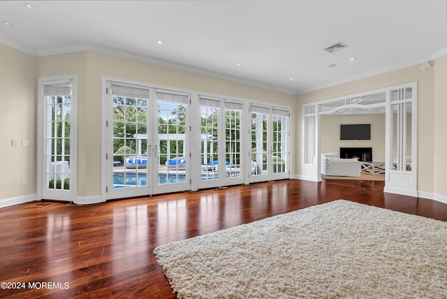 unfurnished living room featuring ornamental molding, hardwood / wood-style floors, and french doors