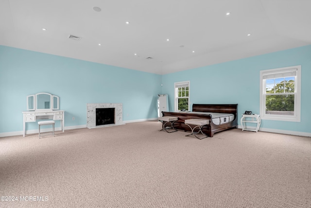 carpeted bedroom featuring a high end fireplace and multiple windows