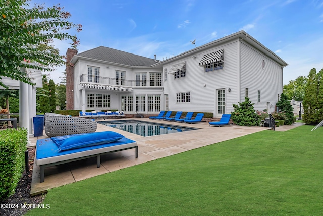 rear view of property featuring french doors, a balcony, a yard, an outdoor hangout area, and a patio