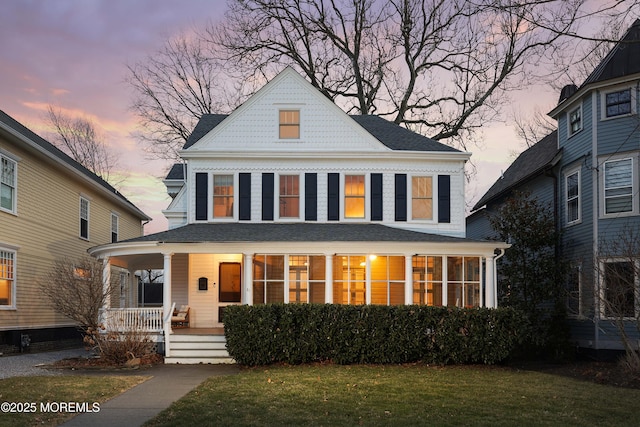 view of front facade featuring a yard, a sunroom, and a porch