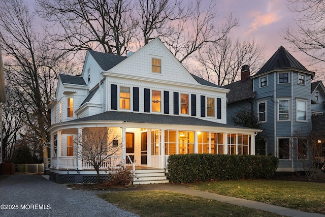 back house at dusk with a sunroom and a yard