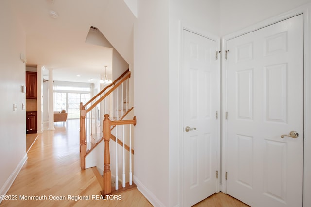 stairs with wood-type flooring and a chandelier