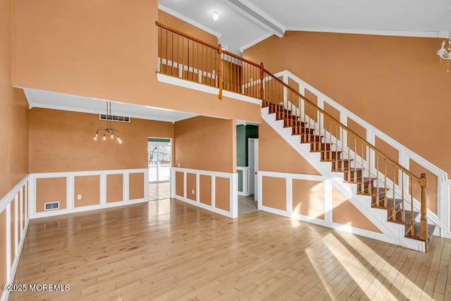 stairs featuring crown molding, an inviting chandelier, wood-type flooring, high vaulted ceiling, and beam ceiling