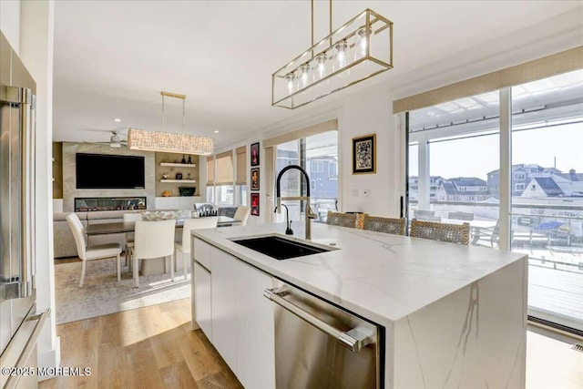 kitchen with sink, white cabinetry, decorative light fixtures, a center island with sink, and stainless steel appliances