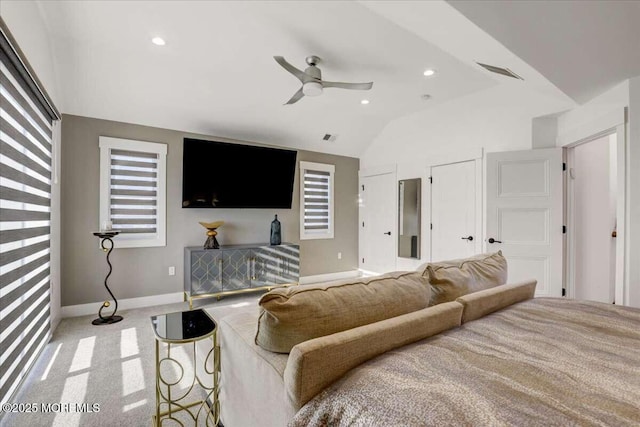 bedroom featuring multiple closets, ceiling fan, vaulted ceiling, and light carpet