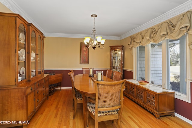 dining area featuring a notable chandelier, crown molding, and light wood-type flooring