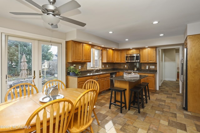 kitchen with french doors, sink, a center island, appliances with stainless steel finishes, and decorative backsplash