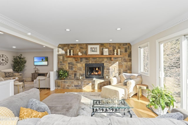 living room featuring crown molding, a stone fireplace, and light hardwood / wood-style floors