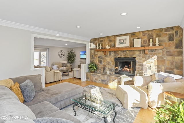 living room with ornamental molding, a stone fireplace, and light hardwood / wood-style flooring