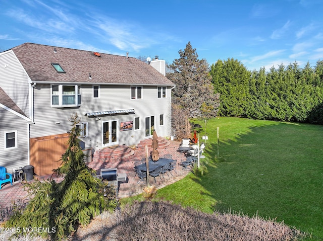 rear view of house with a jacuzzi, a lawn, and a patio