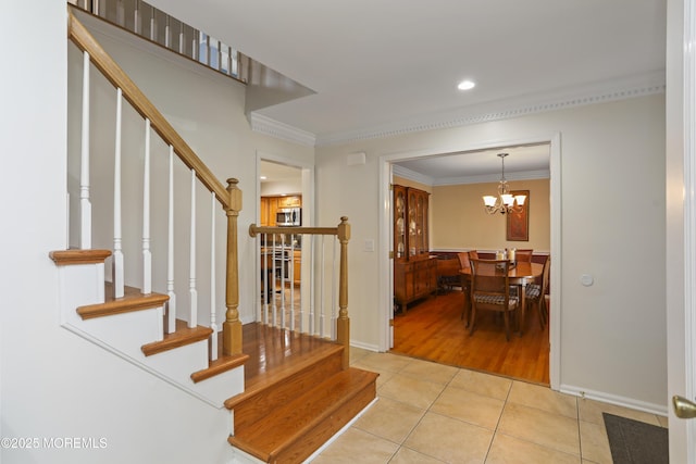 stairs featuring tile patterned flooring, ornamental molding, and a notable chandelier