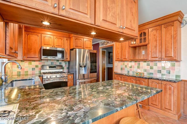 kitchen featuring sink, light tile patterned floors, a breakfast bar, stainless steel appliances, and dark stone counters