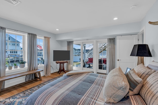 bedroom featuring multiple windows, hardwood / wood-style flooring, and access to outside