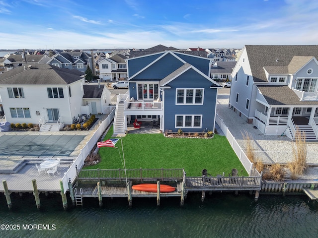 rear view of property featuring a water view and a lawn